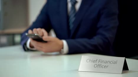 Male-chief-financial-officer-texting-on-smartphone,-viewing-business-files