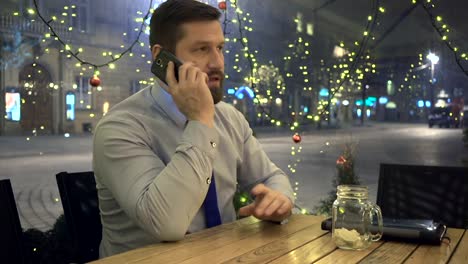 Businessman-calling-by-smartphone,-at-night,-in-cafe,-portrait,-christmas