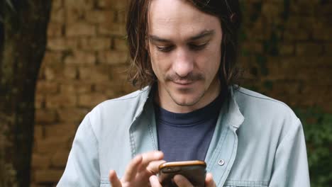 Millennial-man-in-his-20s-or-30s-using-one-hand-to-type-on-smart-phone