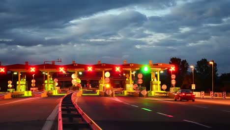 Carretera-coche-Paytoll-en-el-amanecer,-las-luces-de-noche-y-Autos-pasando-por-cabinas-de-peaje,-pagar-por-usar-la-carretera-y-autopista