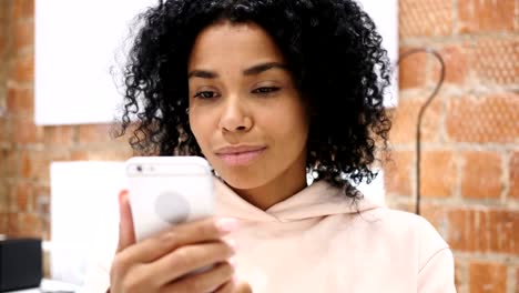 Afro-amerikanische-Frau-bei-der-Arbeit-Surfen-Smartphone-im-Büro