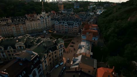 Zángano-de-la-cámara-se-mueve-bajo-techos-de-edificios-en-antigua-europeas-callejuelas-con-casas-de-colores-y-los-peatones-al-atardecer-4K