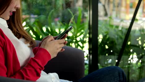 young-woman-wearing-red-cardigan-using-smartphone-for-social-networking.-girl-typing-text-message-on-application-in-mobile-phone.-technology,-communication,-people,-lifestyle-concept