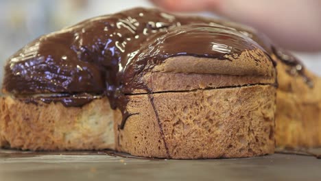 Pastry-Chef-Hände-glasiert-Osterkuchen-süßes-Brot-mit-Schokolade,-Nahaufnahme-auf-der-Arbeitsplatte-in-der-Konditorei