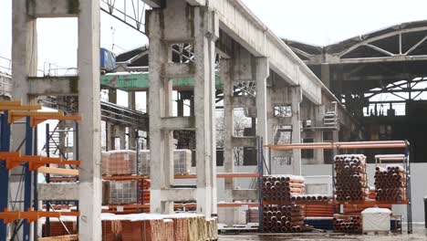 Materiales-de-construcción-para-la-venta-almacenados-en-estantes-de-metal-al-aire-libre-en-un-patio-de-almacén-junto-con-plataformas-de-madera-para-carga,-almacenaje-y-distribución