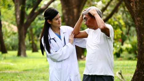 Young-female-doctor-talking-to-senior-patient-in-hospital-garden