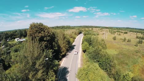 Toma-aérea-del-viejo-coche-del-estilo-del-montar-a-caballo-en-el-bosque-a-través-de-hightway