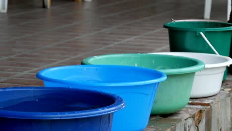 Variety-of-plastic-basins-with-water-standing-on-the-street