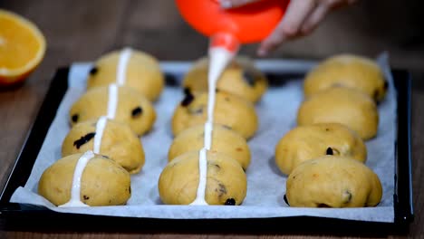 Bollos-de-masa-crudas.-Listos-para-hornear-caseros-Pascua-tradicional-hot-cross-bollos-de-papel-de-hornear.-Las-manos-hacen-una-cruz.