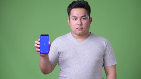 Young-handsome-overweight-Asian-man-against-green-background