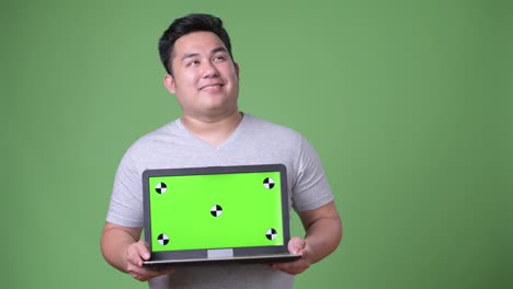 Young-handsome-overweight-Asian-man-against-green-background