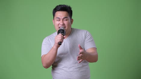 Young-handsome-overweight-Asian-man-against-green-background