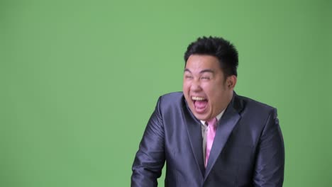 Young-handsome-overweight-Asian-businessman-against-green-background