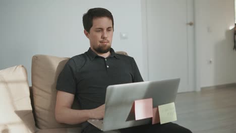 adult-guy-works-as-a-freelancer-on-a-laptop-in-his-apartment-where-there's-a-cat