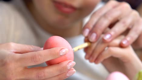 Teacher-helping-to-little-girl-painting-patterns-on-Easter-egg,-preparations