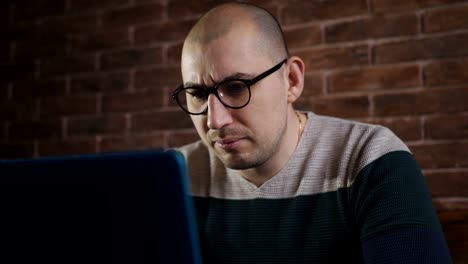 Passionate-man-with-glasses-working-with-laptop-in-the-office.-A-male-writer-is-typing-text-on-laptop-keyboard,-close-up.