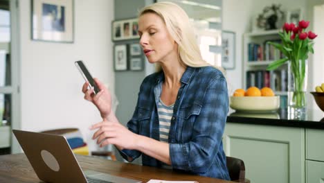 Hermosa-mujer-rubia-escribiendo-en-la-Laptop-y-hablando-por-teléfono-inteligente