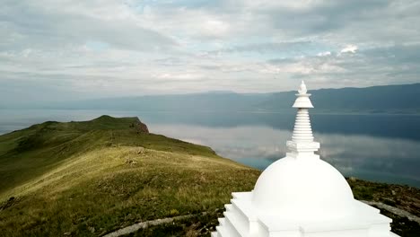 Aerial-Close-Unique-Buddhist-stupa-historic-monument-symbol-spire-top-mystical-ritual-costal-Ogoi-Island-Lake-Baikal-rock-Burkhan-landscape-mountains-Shamanic-worship.-Drone-Around