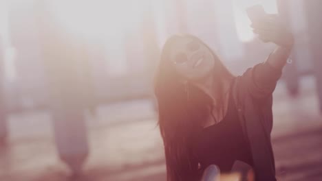 Young-Asian-woman-with-skateboard-taking-selfies-on-smartphone