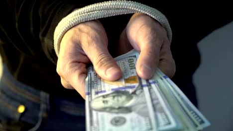 male-hand-bound-with-the-rope-holding-pile-of-money-american-dollar-bank-notes,-financial-rectrictions-concept