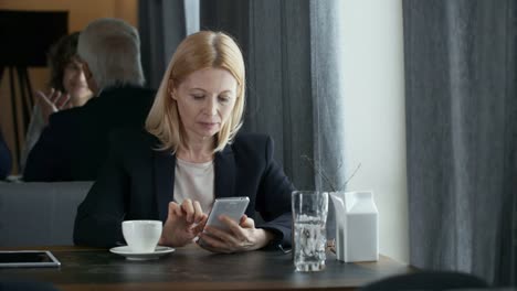 Senior-Businesswoman-Using-Smartphone-in-Restaurant