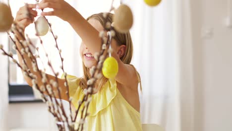 girl-decorating-willow-by-easter-eggs-at-home