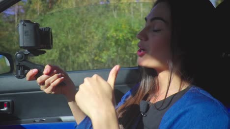 Young-brunette-woman-vlogger-in-a-car-shooting-video-for-her-channel-with-camera