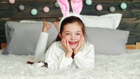 Smiling-girl-with-bunny-ears-lying-on-the-bed