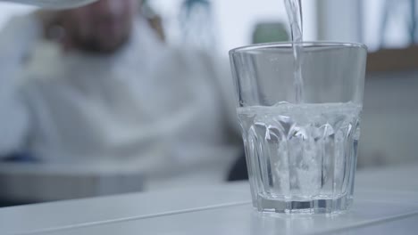 Angenehmer-Kellner-gießt-Trinkwasser-in-ein-Glas,-bevor-er-Hauptgericht-bringt