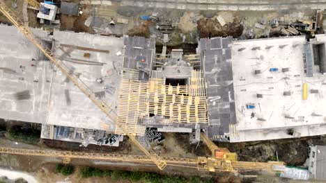 Construcción-de-un-edificio-de-gran-altura,-una-vista-desde-la-parte-superior-con-un-Dron.-Los-obreros-construyen-una-casa.-Panorama-desde-la-parte-superior-de-la-obra