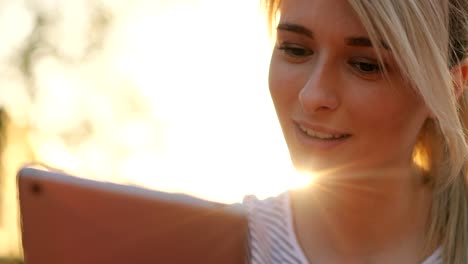 Close-up-portrait-of-young-female-student-using-tablet-computer-in-the-park.-Girl-doing-online-shopping-on-tablet-pc