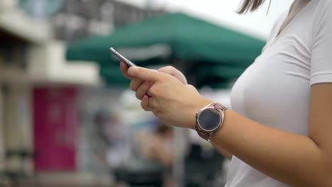 Asian-woman-using-smartphone-outdoors-public-park.-Slow-motion-close-up.-searching-internet,-online-technology.