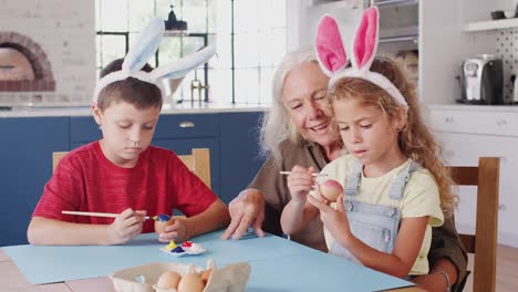 Großmutter-mit-Großkrebsen,-die-Kaninchen-verzieren,-Ostereier-gemeinsam-zu-Hause