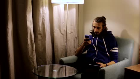 Handsome,-young-man-with-tablet-computer-sitting-on-chair-at-home