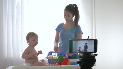 videoblog-streaming-live,-cute-baby-boy-with-mom-played-by-educational-toys-and-filming-new-episode-for-vlog-in-streaming-live-on-smartphone-for-subscribers-in-social-networks