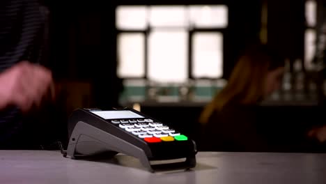 Close-up-shot-of-woman-swipes-credit-card-through-terminal-machine-performing-payment.