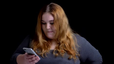 Closeup-shoot-of-young-overweight-caucasian-female-browsing-on-the-phone-and-reacting-top-social-media-posts-then-looking-at-camera-and-smiling