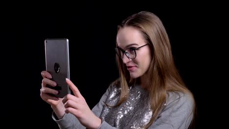 Closeup-shoot-of-young-attractive-hipster-female-in-glasses-having-a-video-call-the-tablet-with-background-isolated-on-black