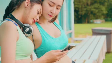 Lifestyle-asiatische-Sportfrauen-halten-Smartphone-spielen-Musik-Entspannung