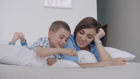 Happy-family-mother-and-child-son-with-tablet-in-evening.-Happy-family-mother-and-child-son-with-tablet-in-evening-before-bed.