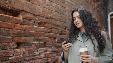 Glückliche-Frau-mit-Smartphone-berühren-Bildschirm-und-lächelnd-gehen-im-Freien