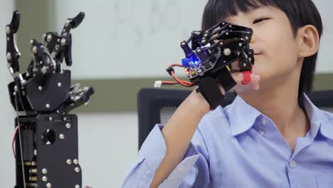 Little-Boy-spielt-mit-Roboterarm-in-einer-Schule.-Er-kontrolliert-es-von-Hand.