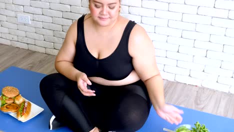 Overweight-young-woman-in-sportswear-choosing-hamburger-rather-than-salad-after-workout