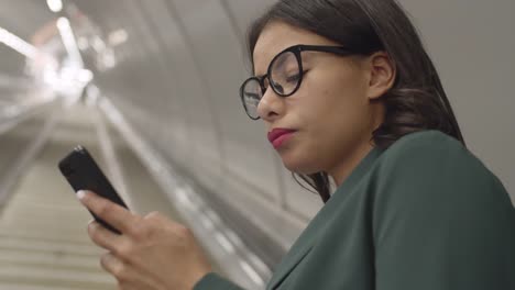 Woman-Using-Cellphone-on-Rolling-Stairs