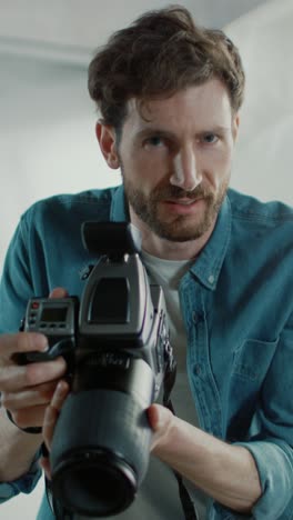 Portrait-of-the-Handsome-Photographer-Holding-State-of-the-Art-Camera-Ready-to-Take-Pictures-with-Softboxes-Lighting-in-Background.-Vertical-Screen-Orientation-Video-9:16