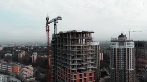 Brick-and-concrete-at-construction-works.-Aerial-drone-view-of-high-rise-residential-complex-construction.-High-crane-near-unfinished-building