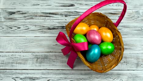 Hand-puts-the-Easter-basket-with-dyed-and-painted-eggs-on-the-table,-concept-of-Christian-feast-Resurrection-Sunday-or-Pascha