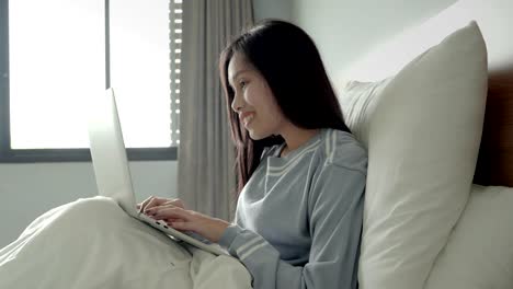 Asian-beautiful-girls-are-using-notebooks-to-play-social-networking-on-the-bed.