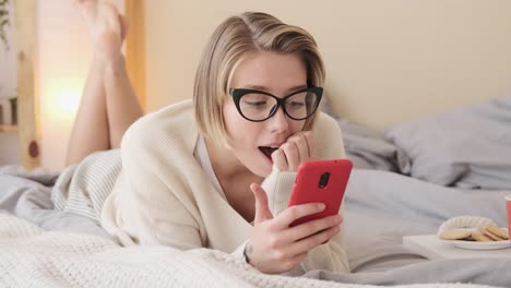 Mujer-sorprendida-usando-el-teléfono-móvil-en-la-cama