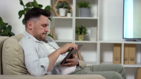 Middle-Aged-Man-Watching-TV-and-Using-Tablet-at-Home